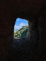 An exquisite view of an expansive landscape can be seen through a unique hole in a rock wall, showcasing the beauty of natures geological formations and the effects of erosion photo