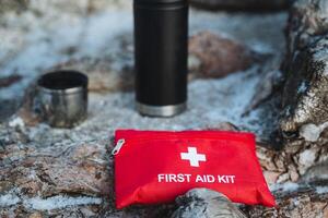 A comprehensive first aid kit is placed on the ground beside a water bottle, which helps keep the beverages cool or warm depending on the content and the situation at hand photo