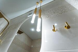 The bathroom features a stylish round mirror accompanied by two elegant light fixtures that are suspended from the ceiling, creating a modern and inviting atmosphere in the space photo