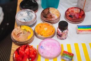 A beautifully arranged table adorned with vibrant face paints and colorful sprinkles, perfect for engaging in creative activities and artistic expression with friends and family photo