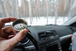 A person confidently holds a compass in their hand while sitting inside a car, likely intending to use it for navigation and to find the correct direction during their journey ahead photo