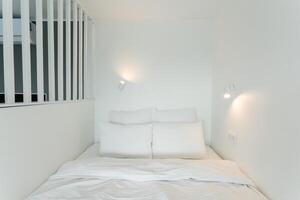 A cozy bed in a small room, adorned with white sheets and pillows photo