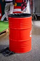 A bright red trash can is currently placed on the side of the road, likely waiting to be picked up by waste management services or disposed of properly at a designated location photo