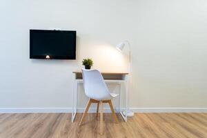 This spacious room features a functional desk with an ergonomic chair, along with a stylish flatscreen TV mounted on the wall for an optimal entertainment and relaxation experience photo