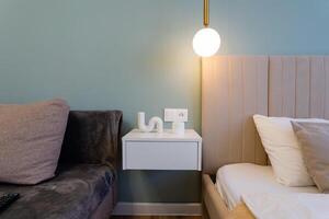 The bedroom includes a cozy bed for restful sleep, a comfortable couch for lounging, a handy nightstand, and a stylish lamp, creating an ideal space for comfort and relaxation photo