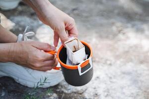 An individual is displaying attention to detail by delicately placing a packet of coffee into a cup on a table, highlighting their focus and precision in the task at hand photo