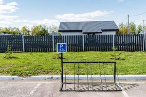 Empty bike rack in suburban residential neighborhood with a wooden fence, house, and greenery in the background. Modern infrastructure for convenience in a scenic urban environment photo
