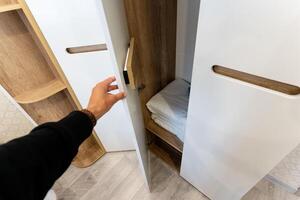 Contemporary Wardrobe Design Featuring an Open Door that Displays Neatly Arranged Shelves and Soft Blankets photo
