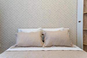 In a beautifully decorated bedroom, there is a cozy bed that features a lovely white headboard complemented by soft and inviting beige pillows, creating a serene atmosphere photo