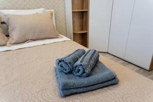 This is a cozy and inviting bedroom featuring neatly rolled towels placed on the bed for added comfort photo
