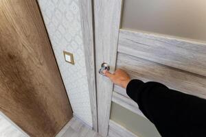 A person is using their hand in a deliberate motion to open a door, engaging in a simple yet essential action that permits access to a new space or room that may hold various possibilities photo