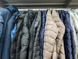 A collection of stylish jackets hangs on a vibrant rack in a colorful store, showcasing unique designs and diverse fabrics for customers to enhance their wardrobe choices photo