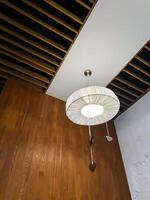 A beautifully designed chandelier is gracefully hanging from the ceiling of a cozy room that features wooden walls, creating a warm and inviting atmosphere with a rustic charm photo