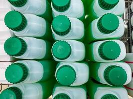 A fascinating collection of a variety of green and white bottles has been meticulously stacked one on top of another, creating a towering display of these colorful cylindrical containers photo