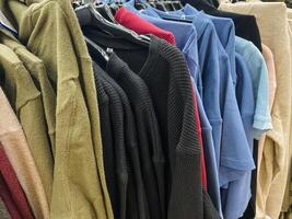 A collection of various clothes, including shirts and pants, are neatly hanging on a sturdy rack, showcasing the latest fashion items available for customers to browse and select from photo
