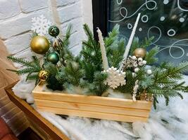 A beautifully crafted wooden box that is filled with an array of colorful and festive Christmas decorations is sitting elegantly on a cozy window sill, brightening up the room photo