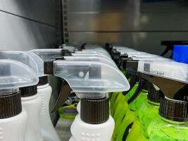 A neat row of various spray bottles is meticulously lined up on a shelf, showcasing an array of colorful fluids ready for use in different applications and purposes, emphasizing cleanliness photo