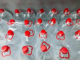 A large stack of assorted plastic water bottles that each have vibrant red caps is neatly arranged on top of one another, showcasing the colorful plastic design and structure of these items photo