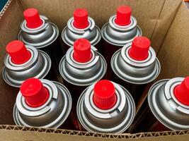 A large cardboard box filled to the brim with a variety of colorful spray cans, all featuring bright red caps that stand out prominently against the materials of the box photo