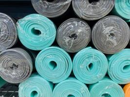 A vibrant and eyecatching stack of yoga mats, made from a variety of colors and different materials, creates a colorful and appealing display of fitness gear for all exercise enthusiasts photo
