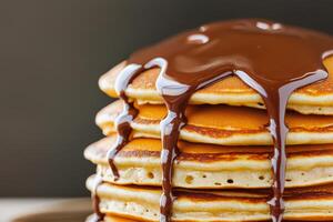 Smooth chocolate drip. Stack of fluffy pancakes drizzled with chocolate sauce. photo