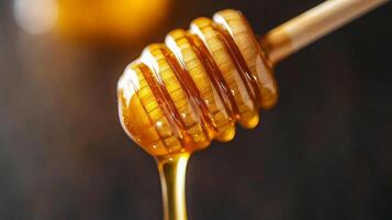 Honey dipping stick. Golden honey dripping from a honey dipper against a dark background. photo