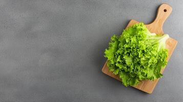 Crisp lettuce bunch. Fresh green lettuce on a wooden cutting board against a textured background. photo