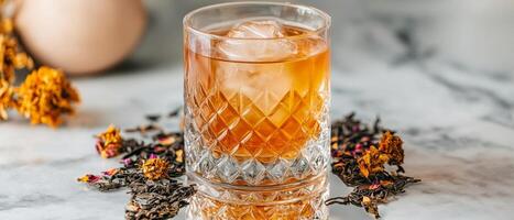 Floral iced tea. Whiskey cocktail with ice and herbs on a marble surface. photo