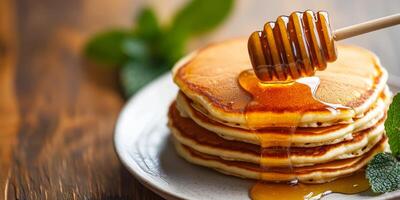 Honey dipping stick. Delicious pancakes drizzled with honey on a wooden table. photo