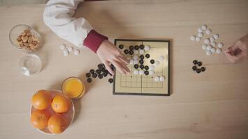 Close up top-view shots of Go, oriental checkers board game on wooden table are played by two Asian players, leisure time hobby, strategy decision and tactic challenge with compete concentrate. video