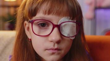Sick ill toddler girl looking at camera, having protective bandage plaster patch scratch on one eye video