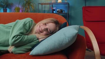 Tired young woman lying down on comfortable couch taking a rest, daytime nap relaxing falling asleep video