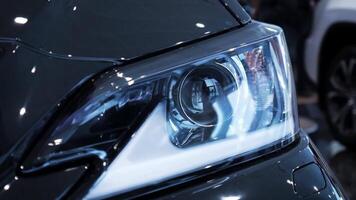 Closeup left car headlight side span of the camera. Stock. Modern techonology auto details with led and xenon elements inside. video