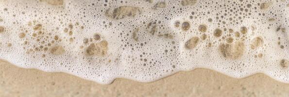 Coastal shoreline with wet sand and foamy sea water creating bubbles and patterns photo