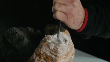 Closeup sculptor works with a special tool for carving stone figures. Cutting stone isolated on black background by hand. Processing with cinematic fragmentation video