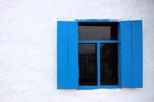 A Charming Blue Window with Shutters set against a Bright White Wall, creating a delightful scene photo
