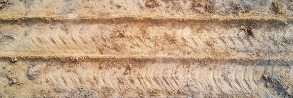 Aerial view of tire tracks on sandy ground surface texture with earth tones photo