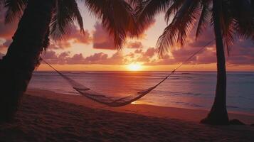 Idyllic tropical beach at sunset with hammock and palm trees by the ocean photo