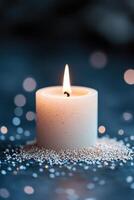 A glowing candle emits a gentle flame, encircled by soft glowing particles on a dark background, creating a tranquil and serene atmosphere perfect for reflection photo