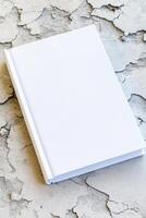 Minimalist depiction of a blank hardcover book on a textured concrete surface suitable for design mockups photo