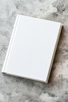 Minimalist book with blank cover placed on textured concrete surface for creative design mockup photo