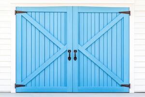 Rustic wooden barn doors painted in weathered blue with rusty metal hinges and soft shadows create a nostalgic countryside backdrop photo