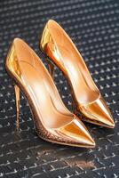 Glamorous high-heeled shoes in a stunning rose gold metallic finish displayed elegantly against a luxurious black textured background photo