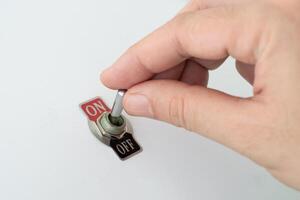 Hand turning a toggle switch from off to on state photo