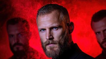 Serious man with beard looking at the camera, two blurred men behind him in red light photo