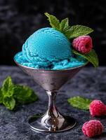A refreshing scoop of blue raspberry ice cream in a martini glass, garnished with mint and raspberries photo