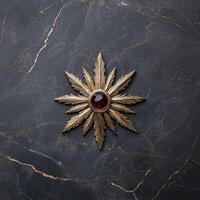 Gold starburst brooch with dark red gemstone on dark marble background photo