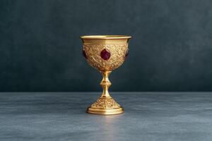 Ornate golden chalice with red gemstones on dark background photo
