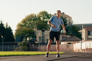 Young man practicing ball skills on an outdoor field during daylight in an urban setting photo