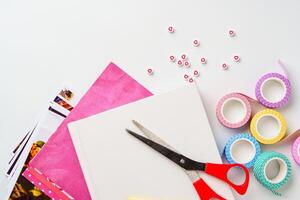 Crafting materials arranged on a flat surface with colorful tape, scissors, and decorative paper for creative projects photo